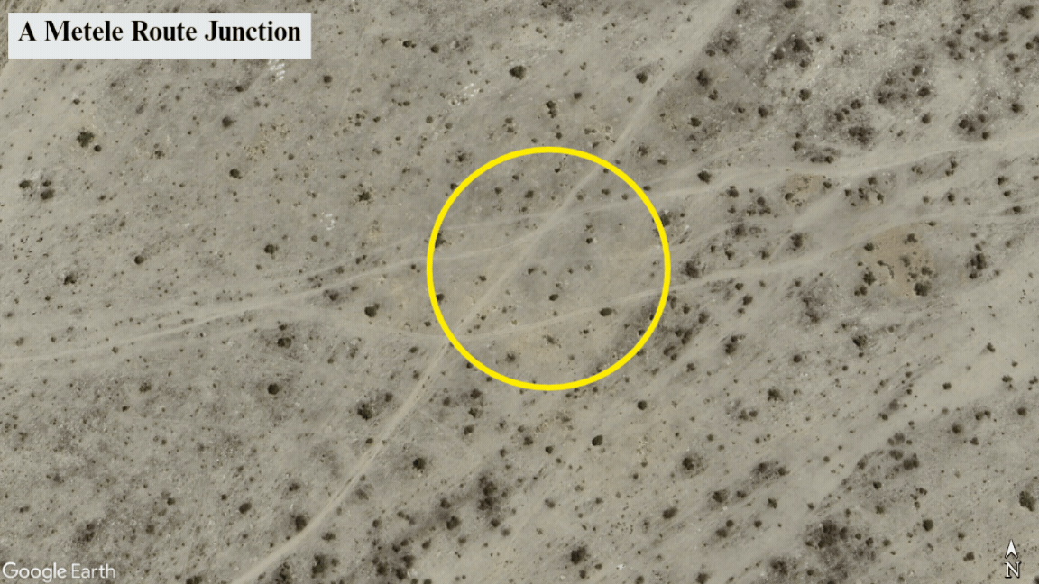 Satellite view of a Metele route junction in a desert area, with paths intersecting. The focus is highlighted with a yellow circle.